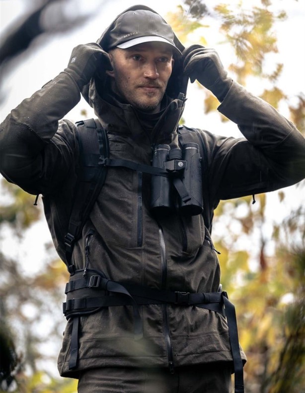 A hunter wearing the Alaska Superior Pro 2027 Solid Brown jacket puts on his hood.