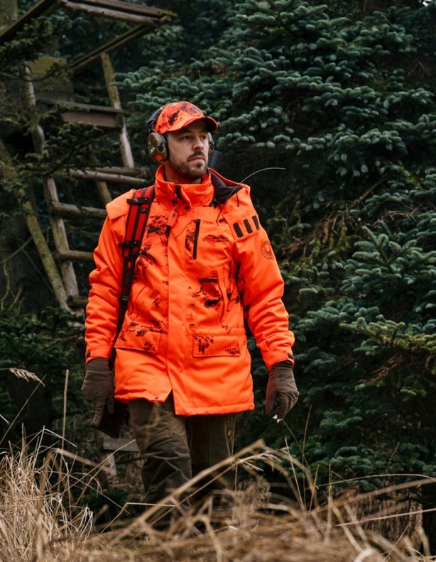 Kurtka Harkila Wildboar Pro Blaze Camo - Myśliwy w kurtce Härkila Wildboar Pro Blaze Camo przy leśnej ambonie.