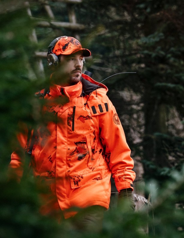 Harkila Wildboar Pro Blaze Camo Jacket - a view of the jacket among the vegetation.